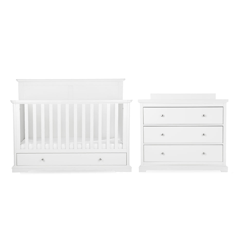 White baby nursery furniture set featuring a convertible crib with built-in storage drawers and a matching three-drawer dresser with small round silver knobs, shown on a plain white background.