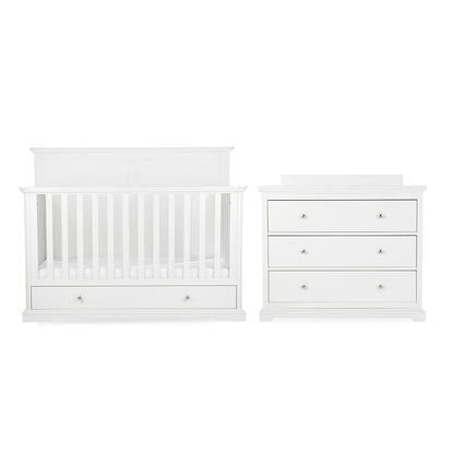 White baby nursery furniture set featuring a convertible crib with built-in storage drawers and a matching three-drawer dresser with small round silver knobs, shown on a plain white background.